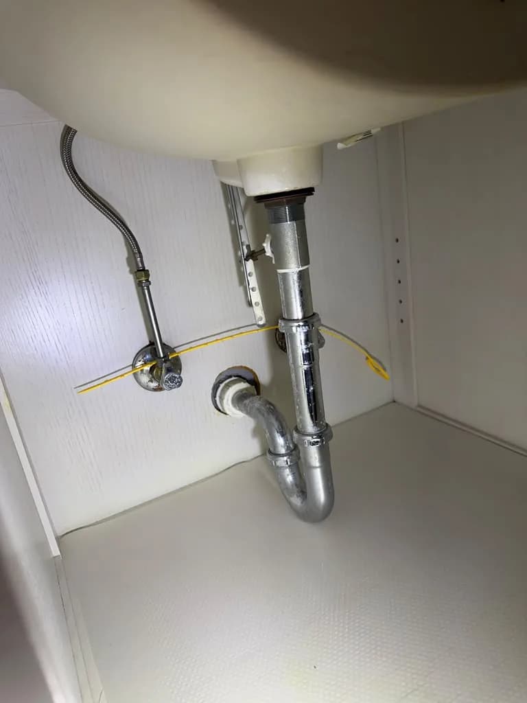 Chrome supply lines and P-trap installed under a bathroom sink