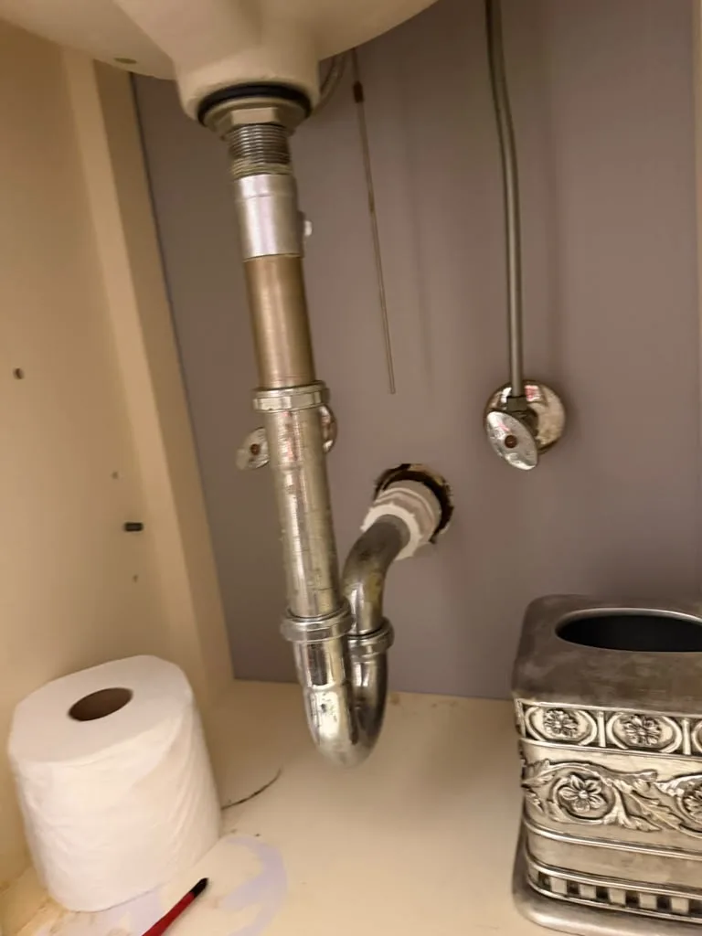 Metal sink drain pipe assembly installed under a bathroom vanity