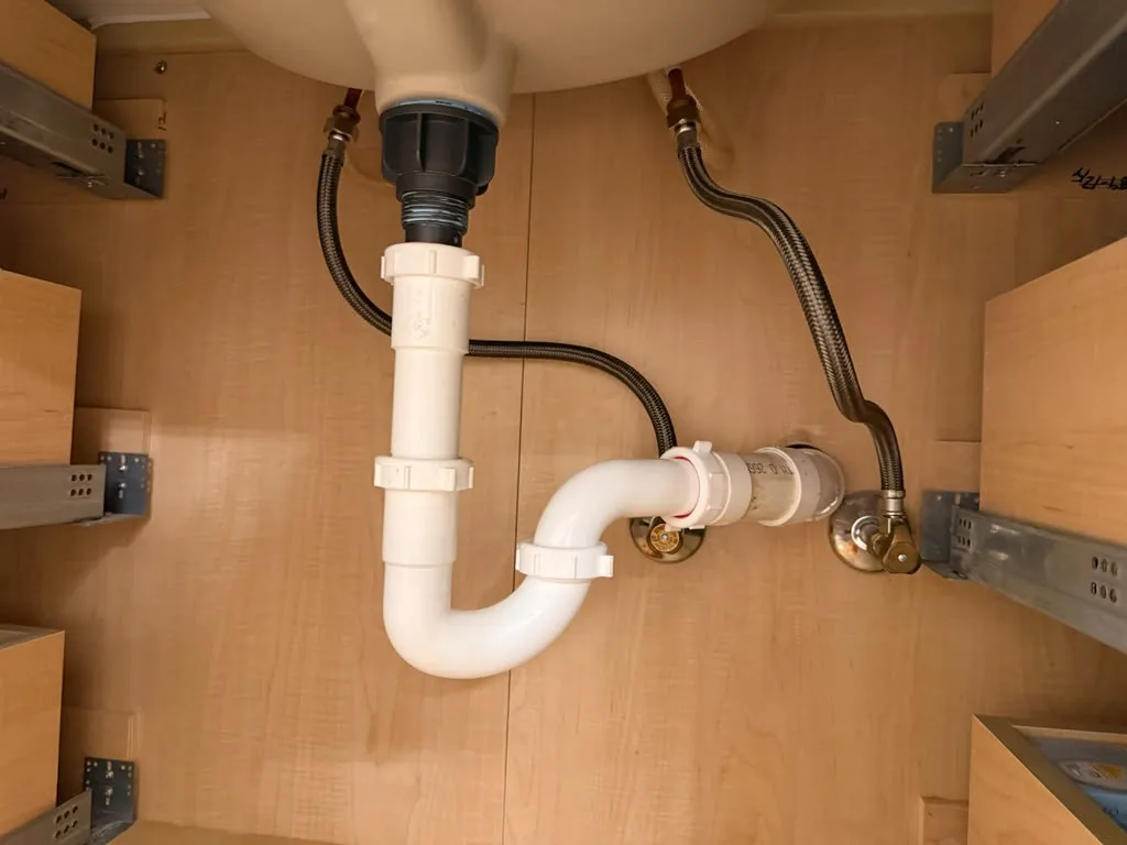 Drain and supply line assembly installed under a bathroom sink cabinet